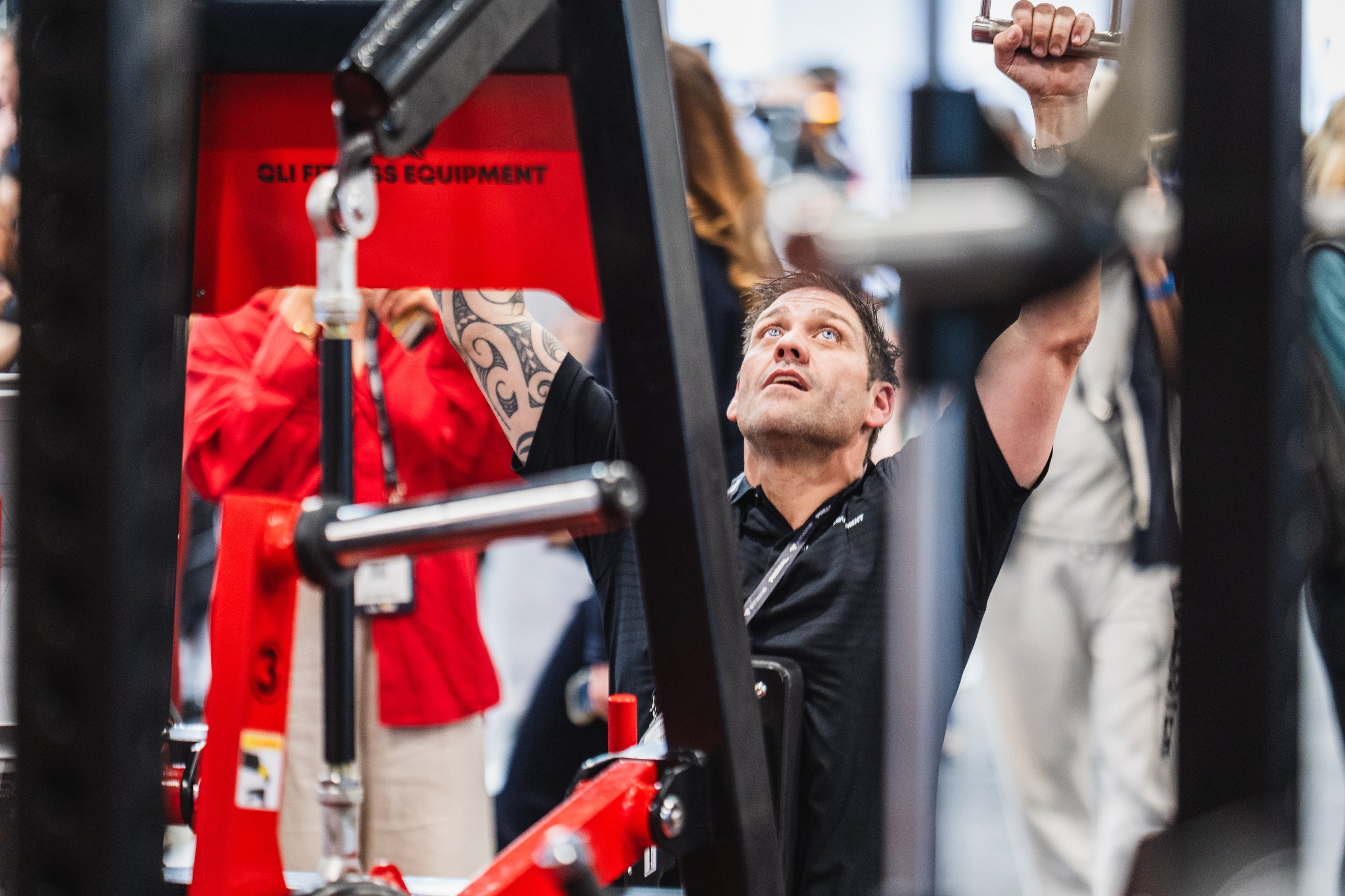 Man testing a strength machine on a fitness equipment stand at AusFitness Expo